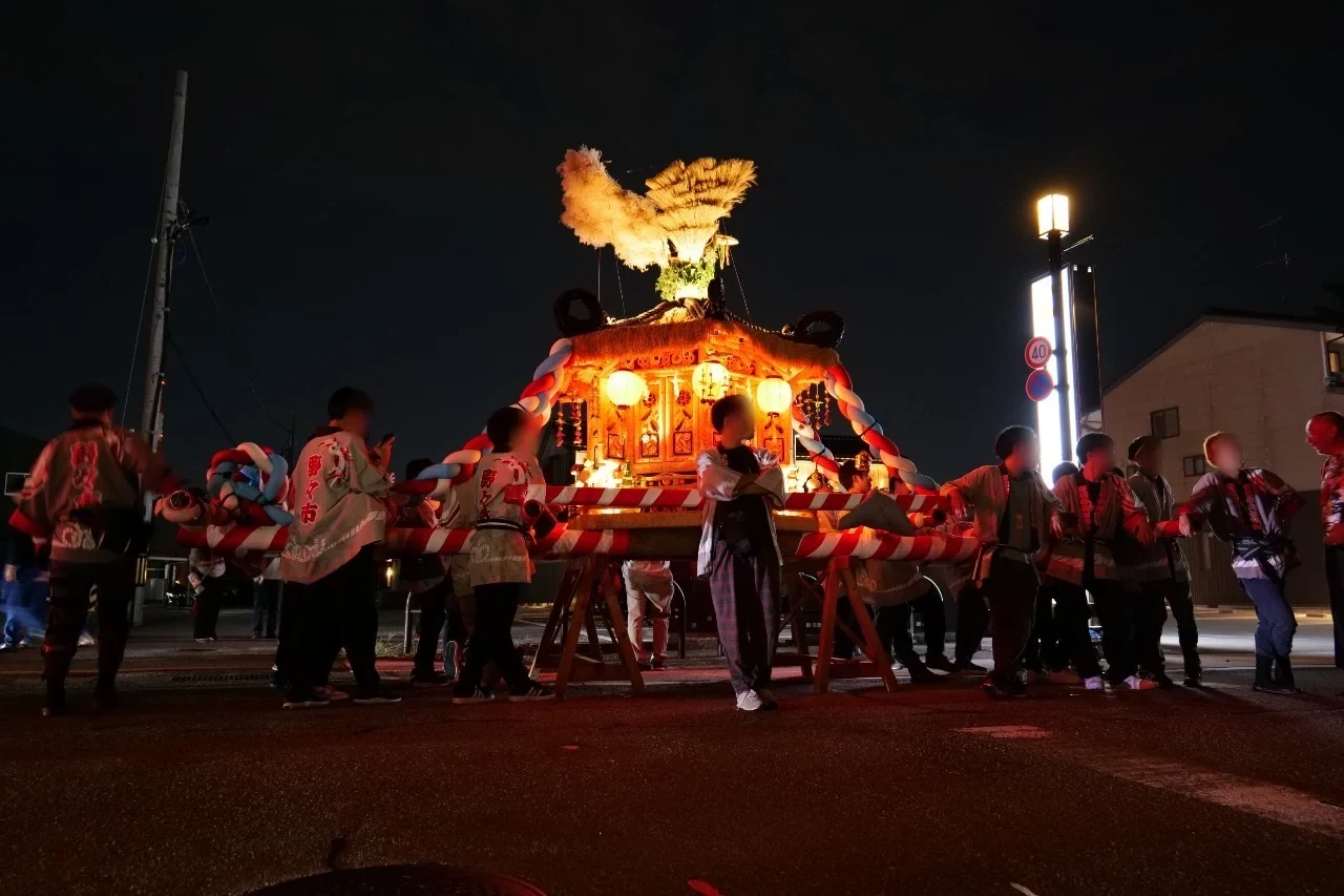 灯りがともった夜の男性神輿と参加者